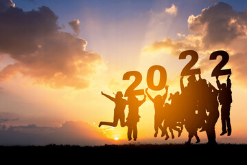 Silhouette of Business teamwork hands up and jump to the beautiful golden sky from text 2022...