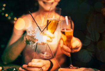 happy couple holding sparkles and champagne glasses New Year party