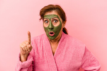 Middle age caucasian woman wearing a facial mask isolated on pink background having an idea, inspiration concept.