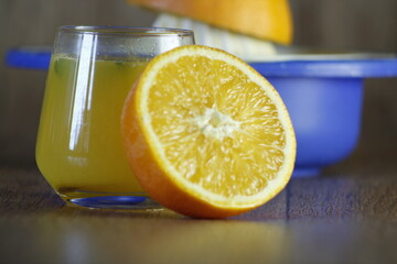 Blue squeezer and a glass of homemade orange juice and slice on wooden texture background. Close up.