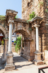 Obraz premium Column and arch of a famous tourist and archaeological site of Antalya is The Emperor Hadrian's gate in the old city. Travel destinations and vacation in Turkey