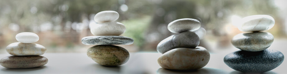 Fototapeta na wymiar Four sets of Zen rocks stacked on the white promenade in the forest garden