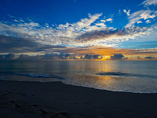 Breathtaking view of a calm sea with low tides washing up ashore under a blue-yellow sunset sky