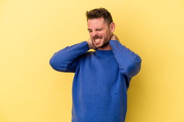 Young caucasian man isolated on yellow background suffering neck pain due to sedentary lifestyle.