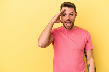 Young caucasian man isolated on yellow background shouts loud, keeps eyes opened and hands tense.