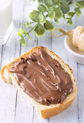 sandwich with chocolate paste on a white wooden background. Delicious breakfast with milk and fresh bread