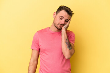 Young caucasian man isolated on yellow background who is bored, fatigued and need a relax day.