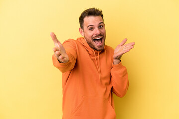 Naklejka premium Young caucasian man isolated on yellow background feels confident giving a hug to the camera.