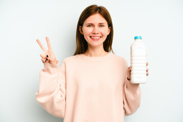 Young English woman holding a bottle of milk isolated on blue background showing number two with fingers.