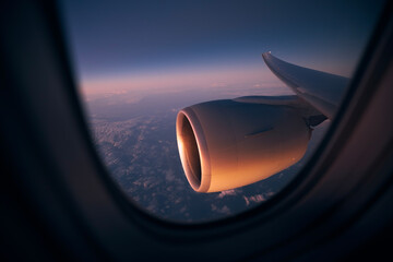 View from window of airplane during night flight above ocean. Selective focus on jet engine..