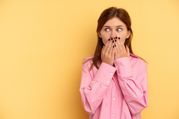 Young English woman isolated on yellow background thoughtful looking to a copy space covering mouth with hand.