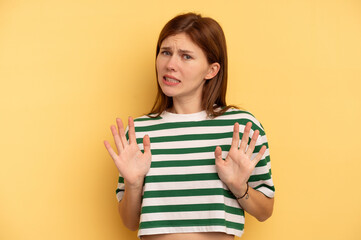 Young English woman isolated on yellow background rejecting someone showing a gesture of disgust.