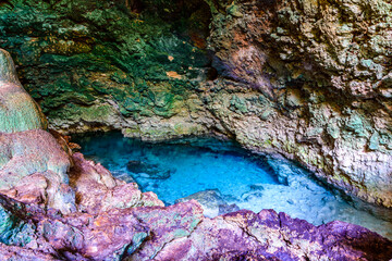 Stalactites and stalagmites in a Kuza cave at Zanzibar, Tanzania. Natural pool with crystal clear water