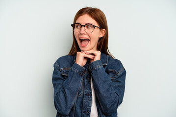 Young English woman isolated on blue background praying for luck, amazed and opening mouth looking to front.