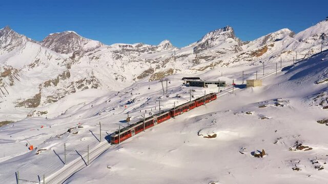 Aerial drone footage of the iconic cogwheel Gornergrat railway in the Zermatt ski resort in the Alps in Valais, Switzerland on a sunny winter day