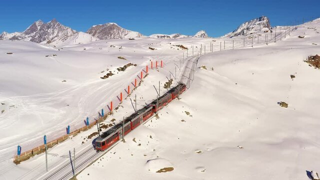 Aerial drone footage of the iconic cogwheel Gornergrat railway in the Zermatt ski resort in the Alps in Valais, Switzerland on a sunny winter day