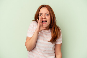 Young caucasian woman isolated on green background shouting excited to front.