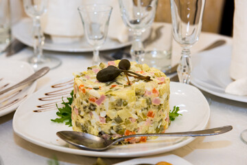 New Year's salad Olivier on the festive table. A table with food served with dishes for guests.