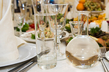 A decanter of vodka on the festive table. A table with food and alcohol served with dishes for guests.