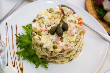 New Year's salad Olivier on the festive table. A table with food served with dishes for guests.