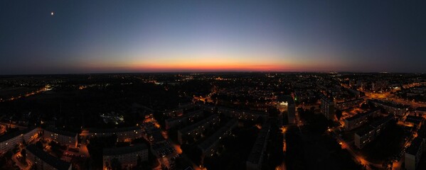 Panoramic aerial view of a city at twilight with glowing streetlights and a colorful horizon. Ideal...