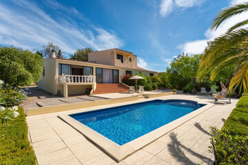 Modern villa with pool and tropical garden with palm trees and rocking chair. The hotel is a hostel...
