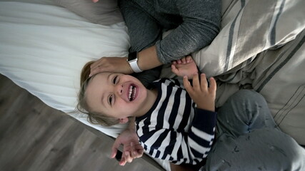 Child laughing in bed together with mother in the morning