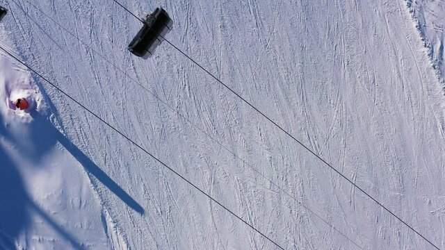 Top down aerial drone footage of skiers and chairlifs on the slope of the Corvatsch mountain ski resort in Canton Graubunden, or Grisons, in the Swiss alps