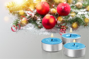 Three burning candles with fir branches with Christmas ornament. Festive background
