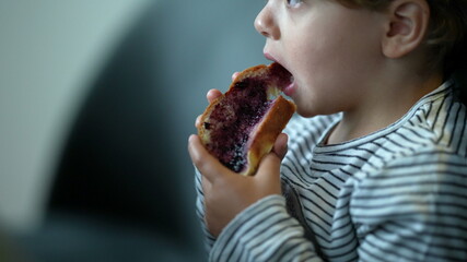 Child eating morning bread with jelly for breakfast