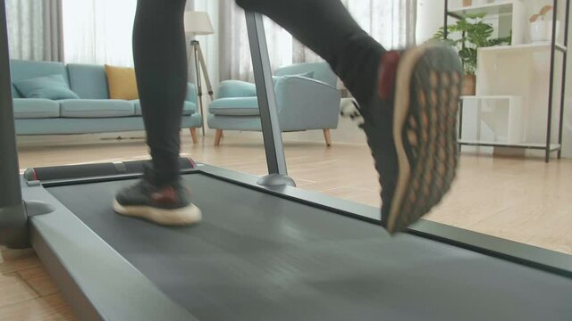 Back View Legs Of Asian Woman Running On A Treadmill At Home
