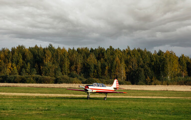 Fototapeta na wymiar Sports light-engine airplane on the field against the sky with clouds. Sports aviation. Airplane
