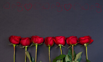 Border made of red roses on dark background.