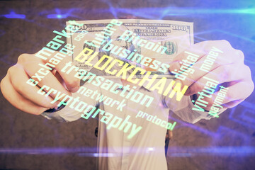 Multi exposure of blockchain theme drawing hologram and USA dollars bills and man hands. Business concept.