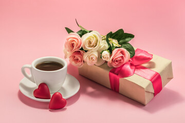 A cup of coffee, two hearts and a bouquet of flowers on a gift box on a pink background. Love, engagement and Valentine's Day concept. Festive banner.
