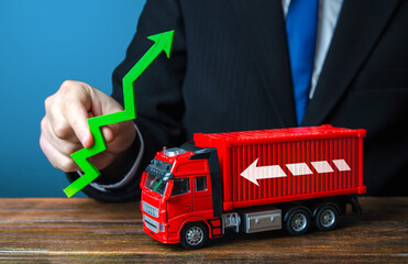 Businessman holds a green arrow up and a truck. Production growth. Import, export. End of...