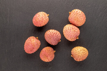 Several ripe sweet Litchi fruits on a slate stone, close-up, top view.