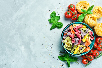 Colored dry pasta in a bowl on a gray stone background. Food. Top view. Free space for text.