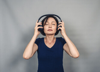 Woman in headphones is fascinated listening to music. Eyes closed with pleasure.