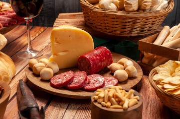 minced table with assorted cold cuts, salami, cheeses, homemade fat bread, peanuts and French fries with wooden plates and wicker basket