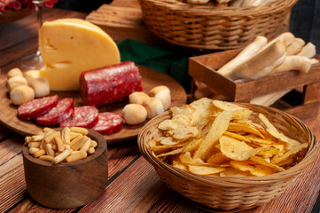 minced table with assorted cold cuts, salami, cheeses, homemade fat bread, peanuts and French fries with wooden plates and wicker basket