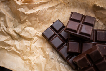 A bar of dark chocolate lies on the paper