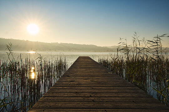 Wooden deck at the shore of a lake in Sempach, Switzerland, surrounded by mountains