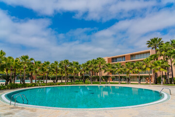 Fototapeta na wymiar Summer luxury round pool near the hotel with palm trees for tourists. Portugal Albufeira Salgados. Summer