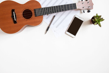 Fototapeta premium Workplace of a musician with a ukulele on a white background, top view, copy space.
