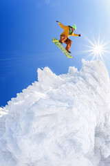 Snowboarder jumping against blue sky in high mountains