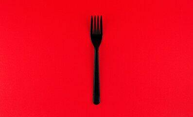 Black plastic fork on red background