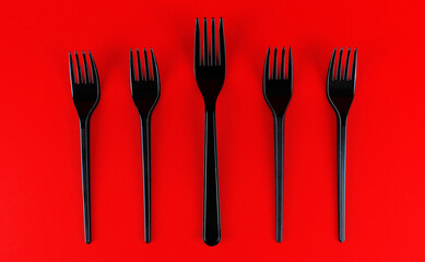 Set of black plastic forks on a red background