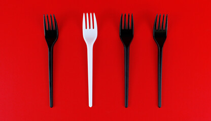 A set of black plastic forks and one white plastic fork. Concept of standing out from the crowd