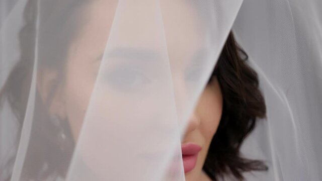 Close-up portrait of a bride in a dress with a veil that covers her head. Happy wedding day.